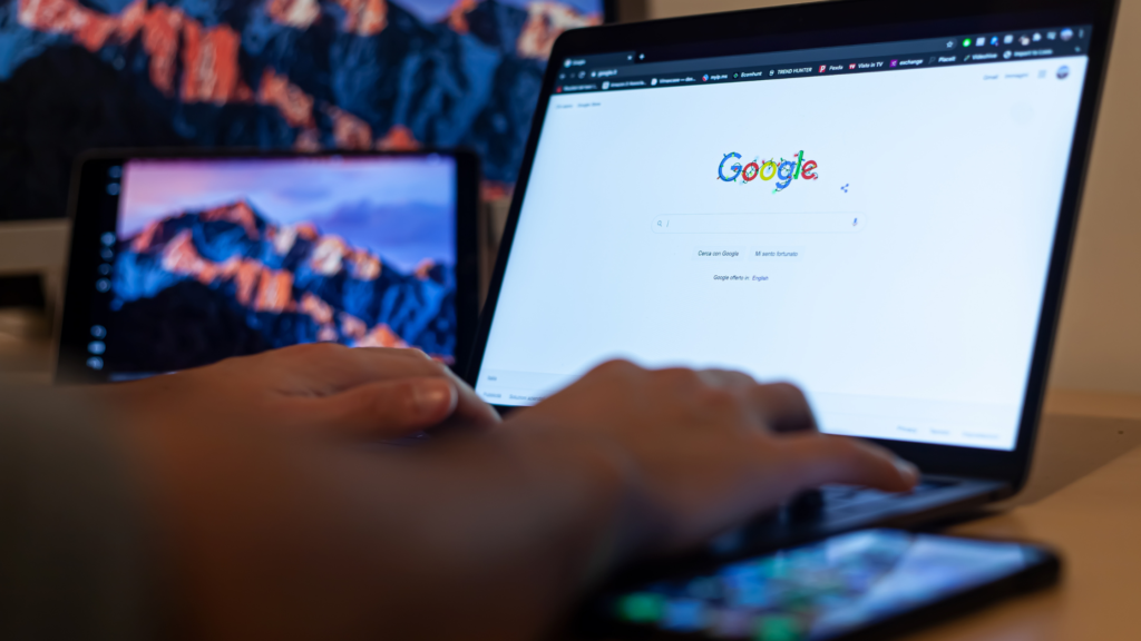Hands typing on a laptop showing the Google homepage